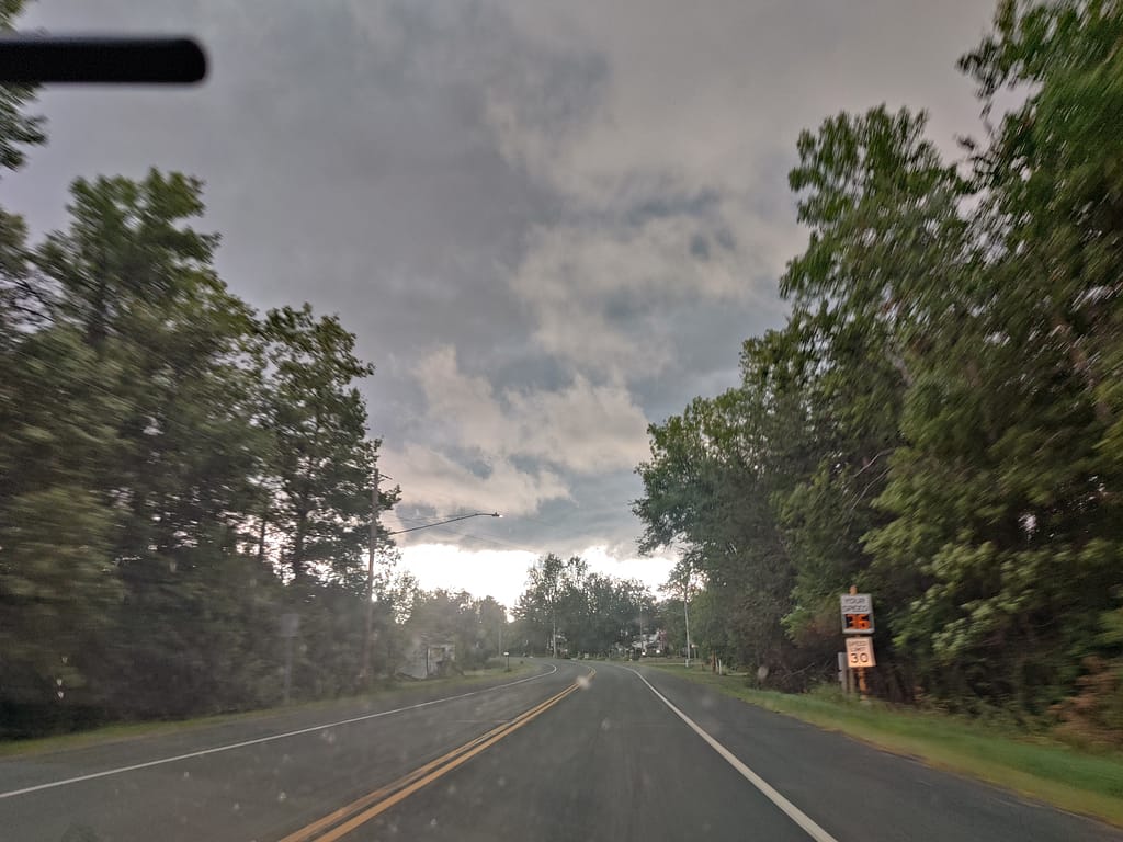 Storm clouds through the windshield on the drive to Wild River State Park. The road is running through and trees are on both sides. 
