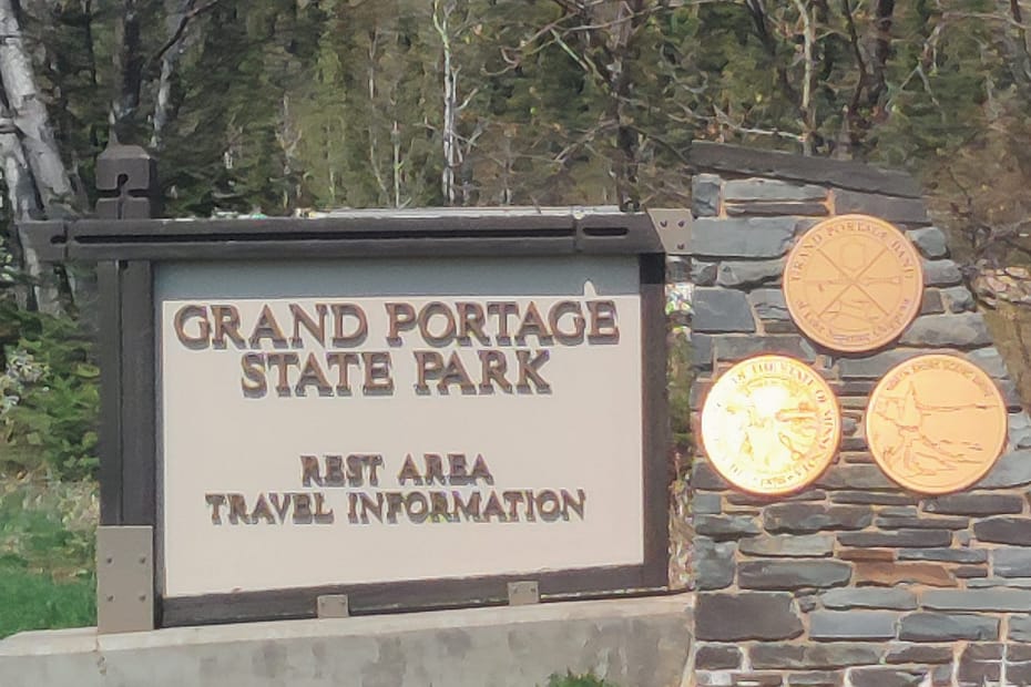 White and brown sign that says Grand Portage State Park rest area travel information